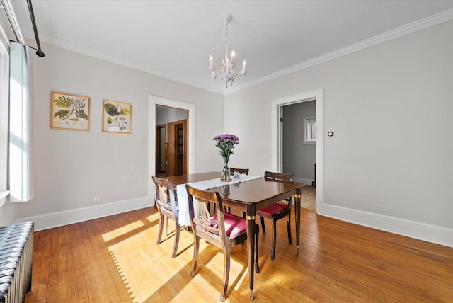 dining room featuring a chandelier, light wood-style flooring, baseboards, and ornamental molding