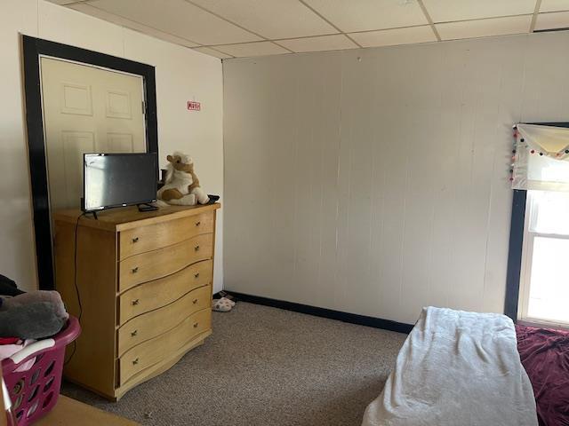 bedroom with a drop ceiling and baseboards