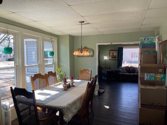 dining area with an inviting chandelier, wood finished floors, and a paneled ceiling