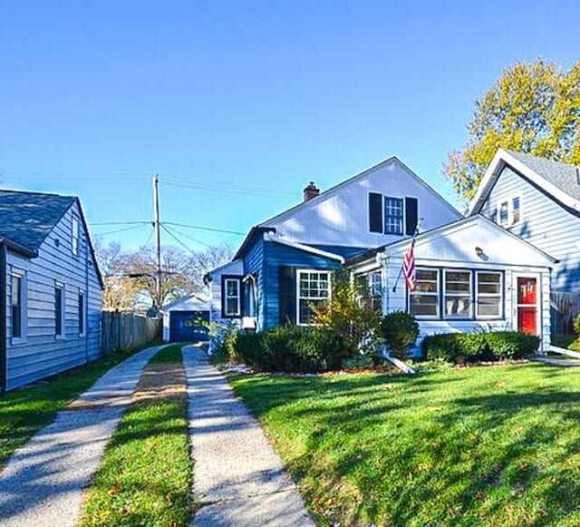 bungalow featuring a front lawn, driveway, and a chimney