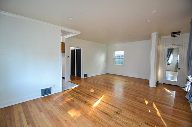 unfurnished living room with visible vents, baseboards, wood finished floors, and ornamental molding