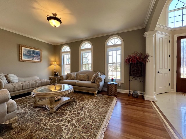 living area featuring baseboards, crown molding, light wood-style floors, and decorative columns