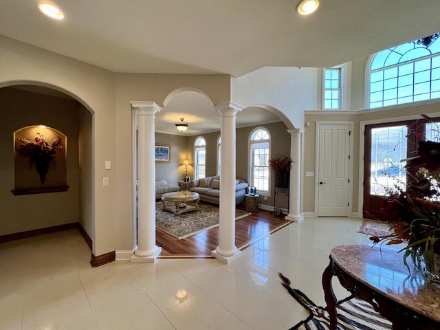 entrance foyer featuring decorative columns, baseboards, arched walkways, and light tile patterned flooring