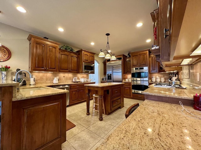 kitchen with light stone countertops, a breakfast bar, a sink, built in appliances, and tasteful backsplash