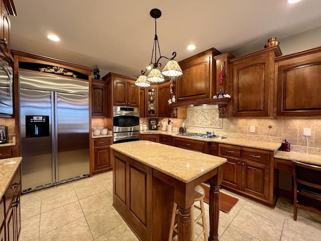 kitchen with light stone counters, light tile patterned flooring, stainless steel appliances, hanging light fixtures, and backsplash