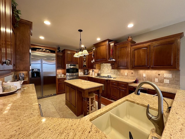 kitchen featuring light stone counters, decorative backsplash, stainless steel appliances, and a sink