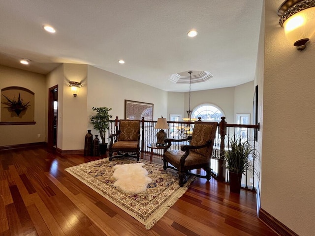 sitting room featuring recessed lighting, a tray ceiling, baseboards, and wood finished floors