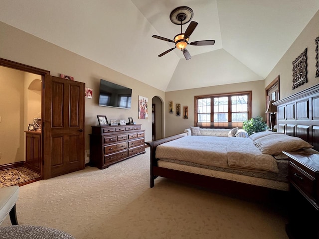 bedroom with high vaulted ceiling, arched walkways, light colored carpet, and a ceiling fan