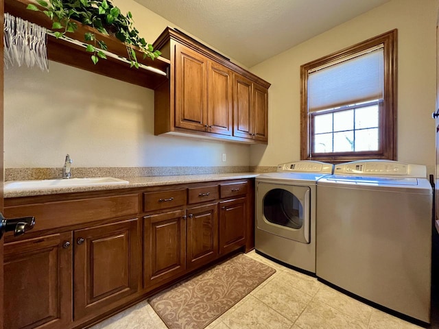 laundry room featuring washing machine and dryer, cabinet space, and a sink