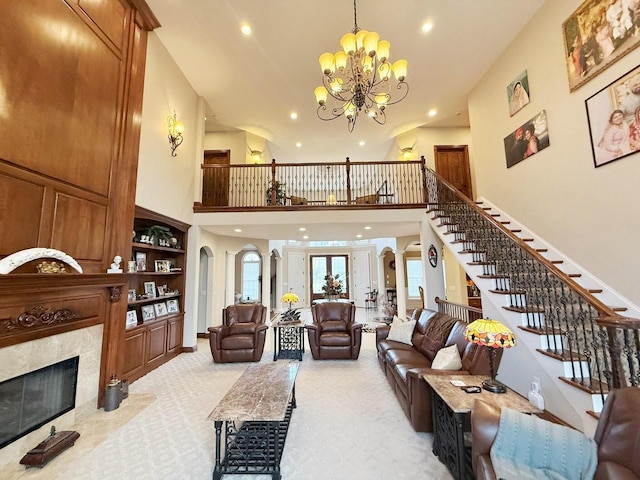 living area featuring light colored carpet, stairs, a premium fireplace, an inviting chandelier, and arched walkways