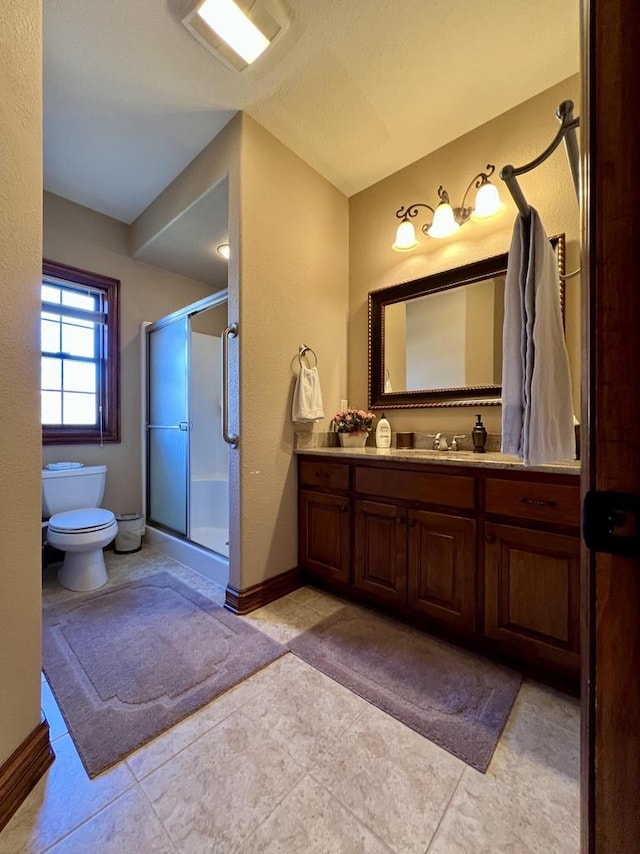 bathroom featuring vanity, a shower stall, toilet, and baseboards