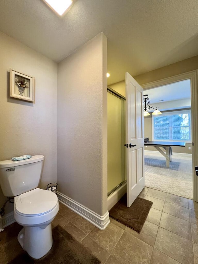 bathroom featuring a shower stall, toilet, and baseboards