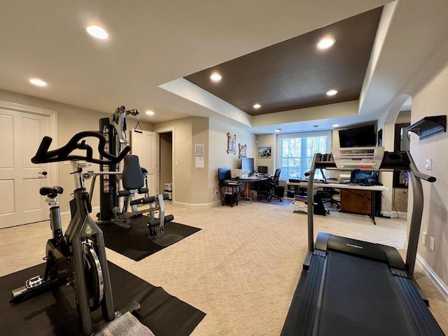 exercise room featuring a raised ceiling, recessed lighting, carpet, and baseboards