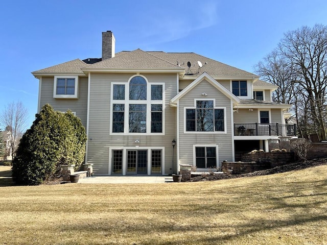 back of property featuring a shingled roof, a yard, a patio area, and a chimney