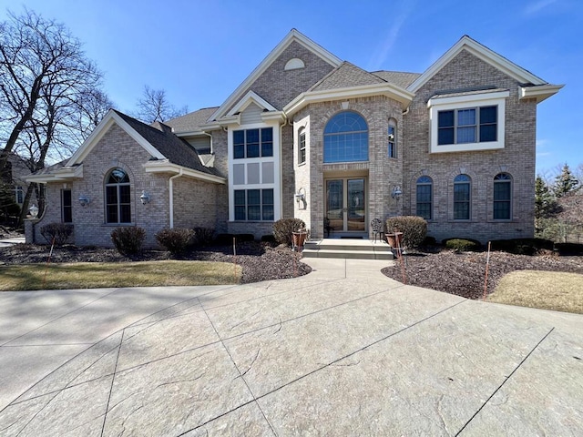 view of front facade featuring brick siding and roof with shingles