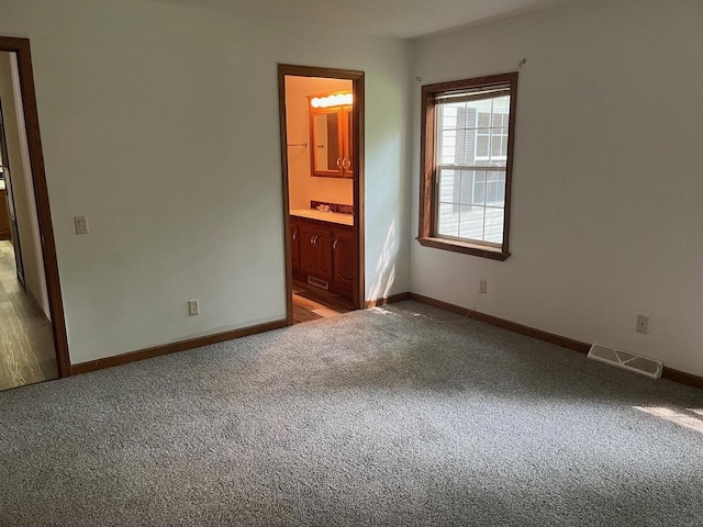 unfurnished bedroom featuring visible vents, baseboards, ensuite bath, and carpet flooring