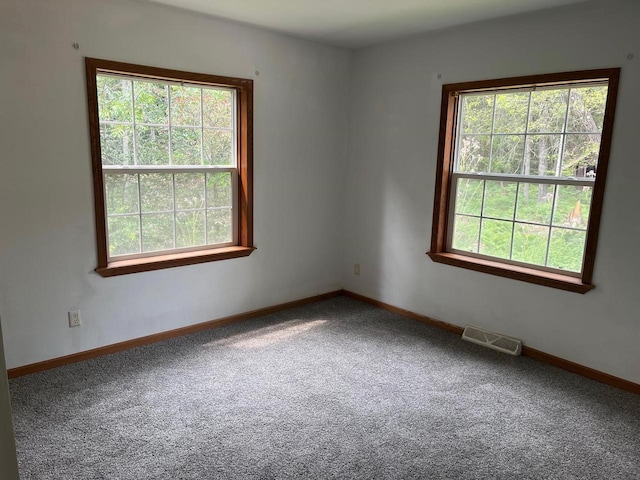 carpeted spare room featuring visible vents and baseboards