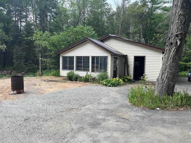 view of front of property with aphalt driveway and a forest view