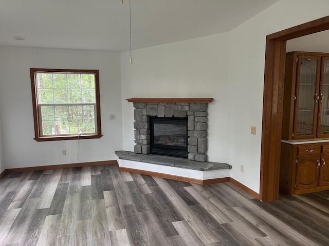 unfurnished living room featuring baseboards, wood finished floors, and a fireplace