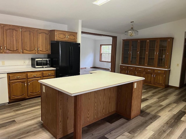 kitchen featuring light wood-type flooring, stainless steel microwave, light countertops, and freestanding refrigerator