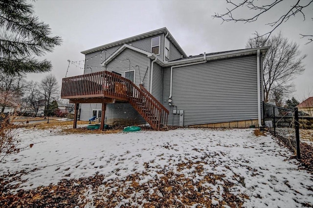 snow covered house featuring stairs, a deck, and fence