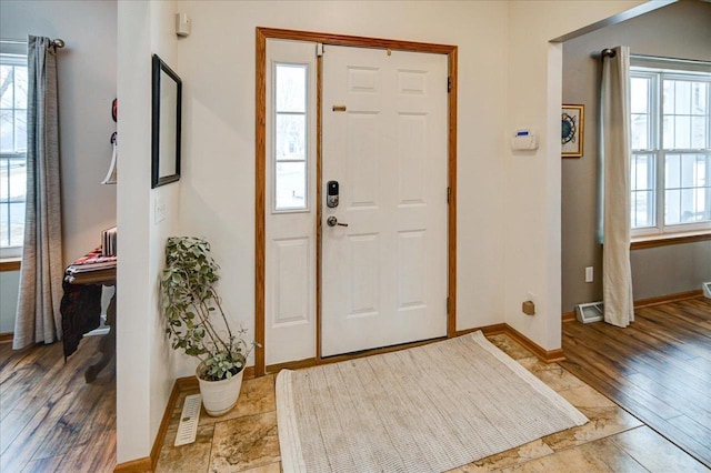 foyer featuring a wealth of natural light, visible vents, light wood-style flooring, and baseboards