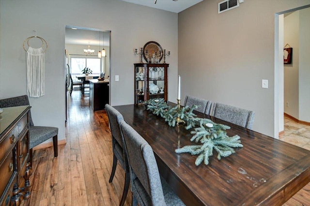 dining space with visible vents, baseboards, an inviting chandelier, and hardwood / wood-style floors