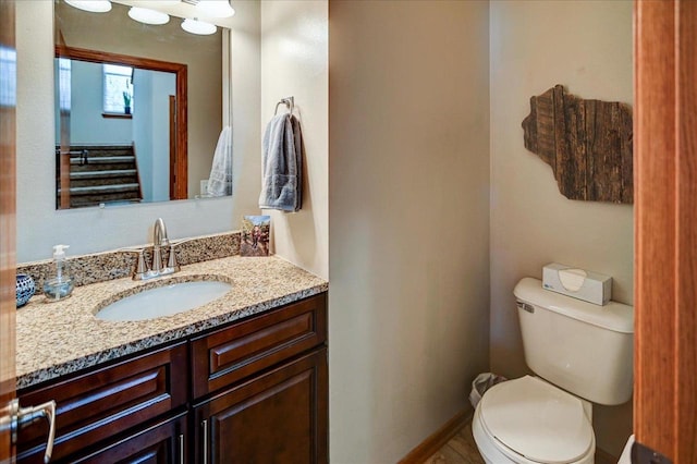 bathroom featuring baseboards, toilet, and vanity