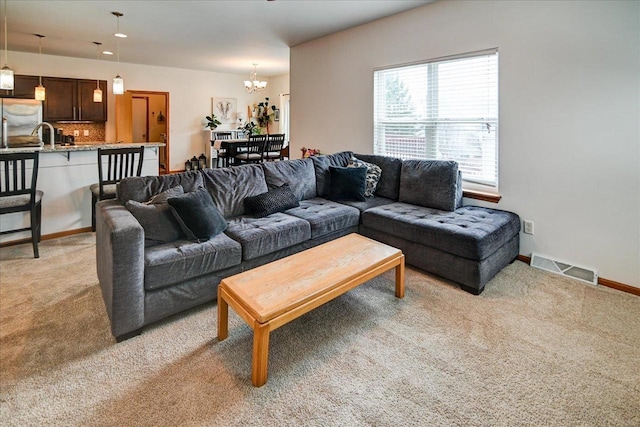 living room with visible vents, light colored carpet, an inviting chandelier, and baseboards