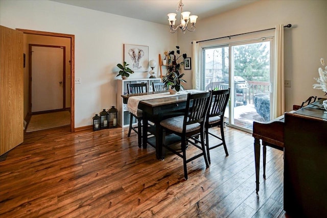 dining space featuring a chandelier, baseboards, and wood finished floors