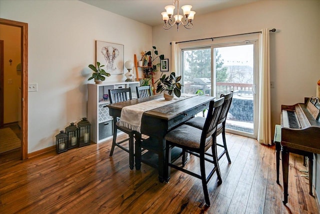 dining space featuring baseboards, wood-type flooring, and a notable chandelier