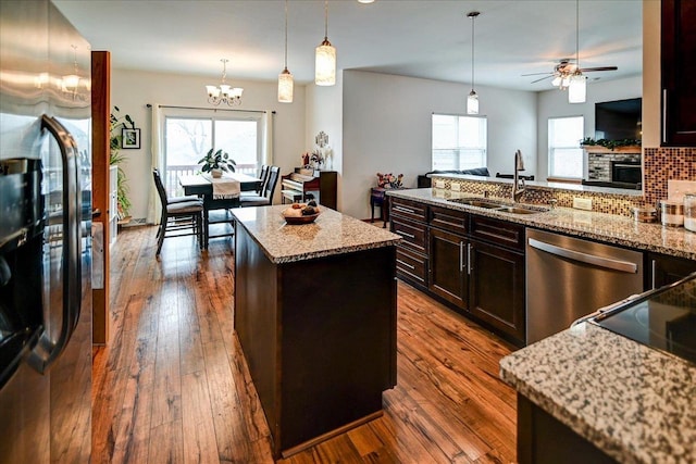 kitchen featuring dark wood-type flooring, refrigerator with ice dispenser, a sink, stainless steel dishwasher, and a center island