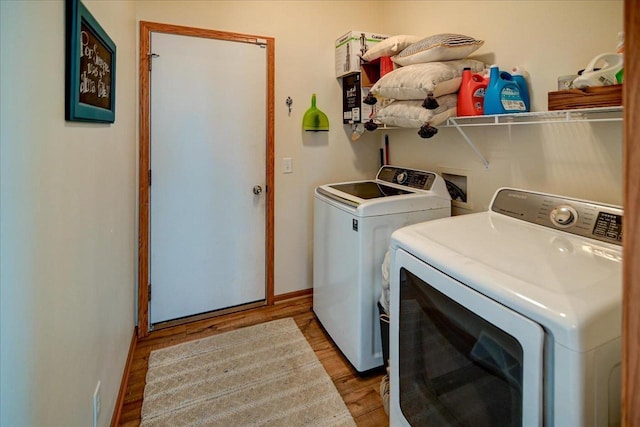 clothes washing area with washer and clothes dryer, laundry area, baseboards, and light wood-style floors