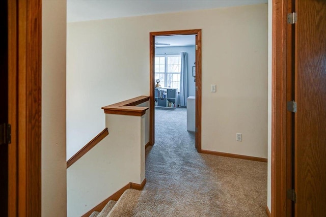 hallway with carpet flooring, an upstairs landing, and baseboards