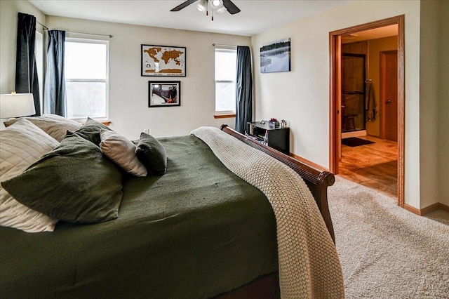 carpeted bedroom featuring ensuite bath, baseboards, and ceiling fan