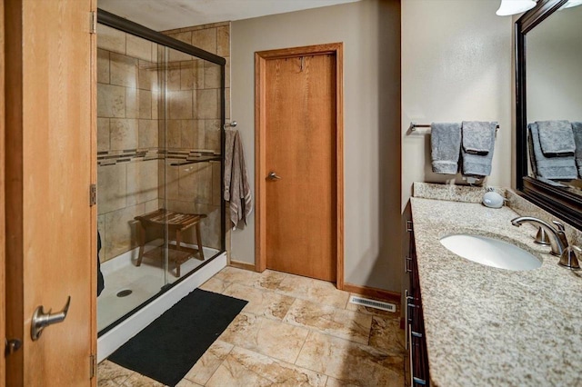 full bath with visible vents, baseboards, a stall shower, stone finish floor, and vanity