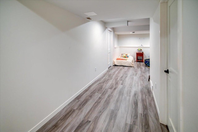 hallway featuring visible vents, baseboards, and wood finished floors