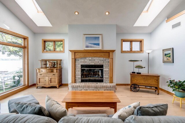 3018 Waubesa Ave, Madison, WI 53711 - living room with a skylight, healthy amount of natural light, a fireplace, vaulted ceiling, and light wood-type flooring