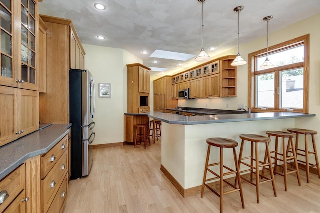 3018 Waubesa Ave, Madison, WI 53711 - kitchen featuring stainless steel appliances, a peninsula, light wood-style flooring, a kitchen bar, and baseboards