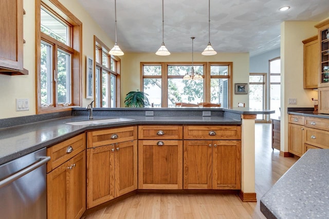 3018 Waubesa Ave, Madison, WI 53711 - kitchen featuring stainless steel dishwasher, a sink, light wood finished floors, hanging light fixtures, and brown cabinetry