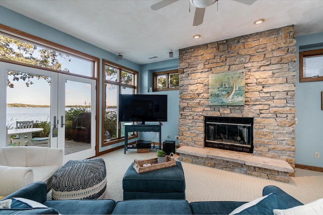 3018 Waubesa Ave, Madison, WI 53711 - carpeted living area featuring baseboards, a ceiling fan, a stone fireplace, and french doors