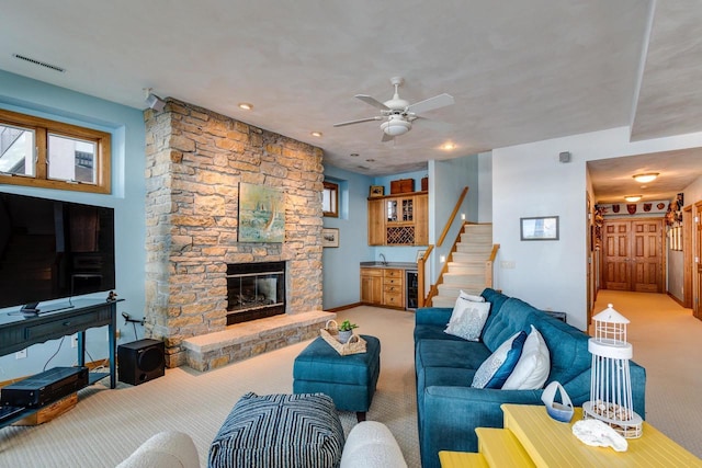 3018 Waubesa Ave, Madison, WI 53711 - carpeted living room with wine cooler, a stone fireplace, stairs, ceiling fan, and baseboards