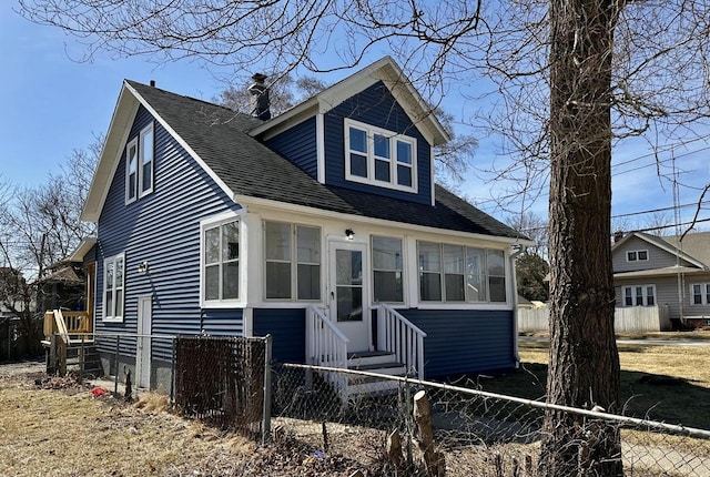 bungalow-style home with entry steps, fence private yard, and roof with shingles