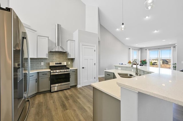 kitchen featuring dark wood-type flooring, gray cabinets, stainless steel appliances, wall chimney exhaust hood, and a sink