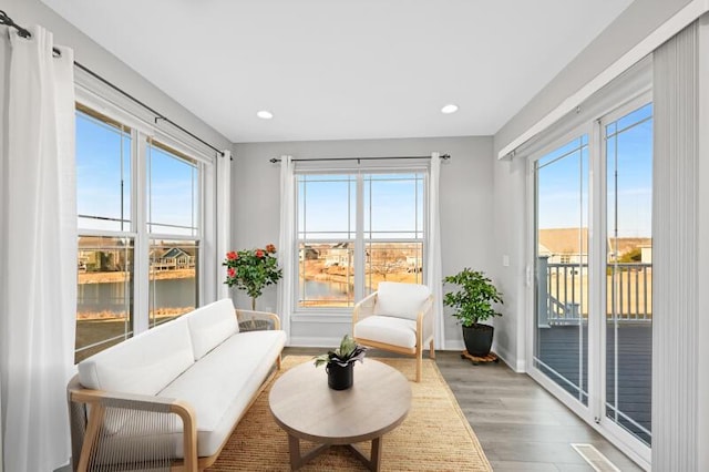 living area featuring a wealth of natural light, light wood-type flooring, and baseboards