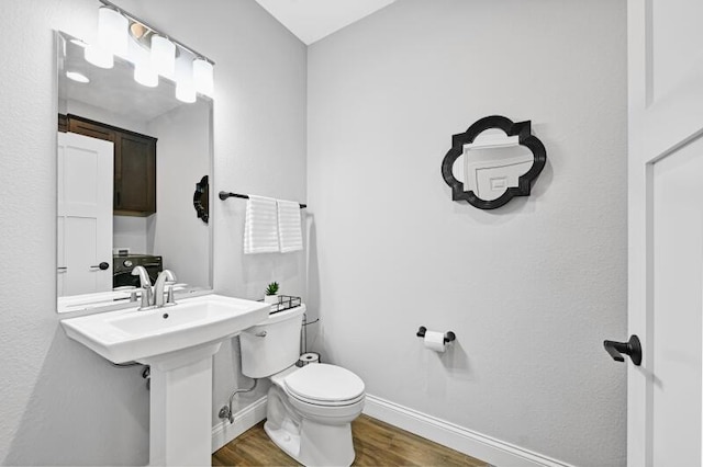 bathroom with a sink, baseboards, toilet, and wood finished floors