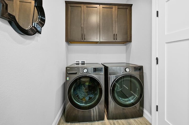 laundry room with wood finished floors, cabinet space, baseboards, and washing machine and clothes dryer