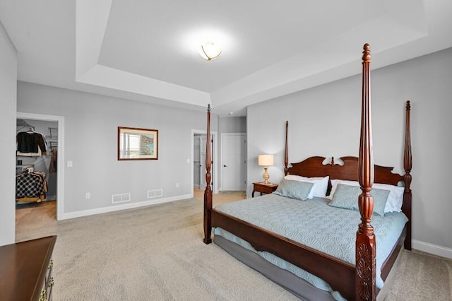 carpeted bedroom featuring a closet, visible vents, baseboards, and a tray ceiling