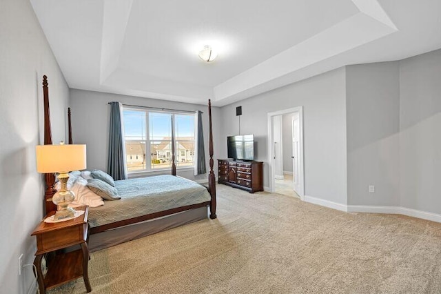 bedroom featuring a raised ceiling, baseboards, and light carpet