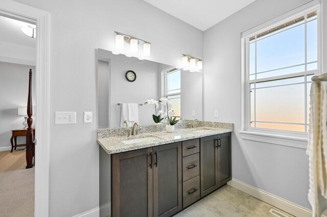 bathroom featuring double vanity, visible vents, baseboards, and a sink